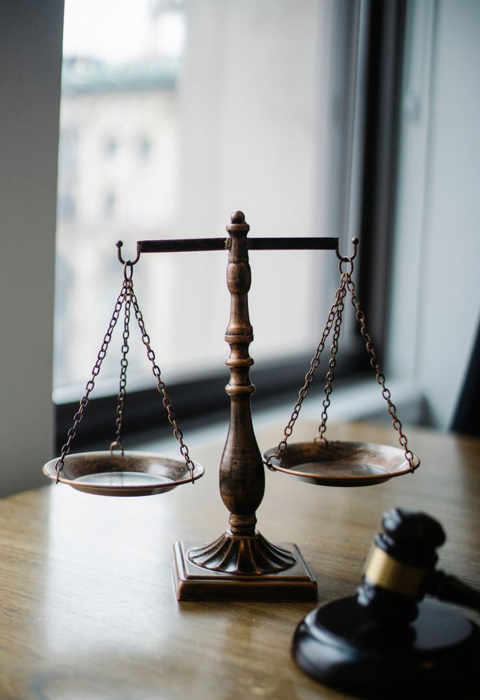 why-choose-us Decorative judgement scale and gavel placed on desk in light lawyer office against window