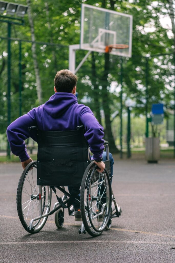 pexels photo 8415878 8415878 A man in a hoodie plays basketball on an outdoor court from a wheelchair, promoting inclusivity.